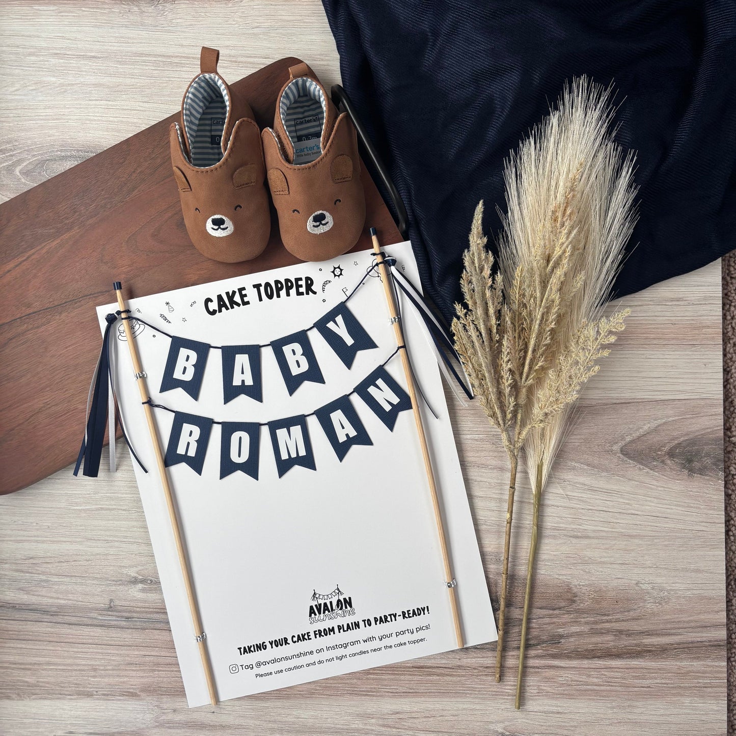 navy blue baby shower cake topper personalized with baby name shown with neutral dried florals and teddy bear baby shoes | personalized cake toppers by Avalon Sunshine