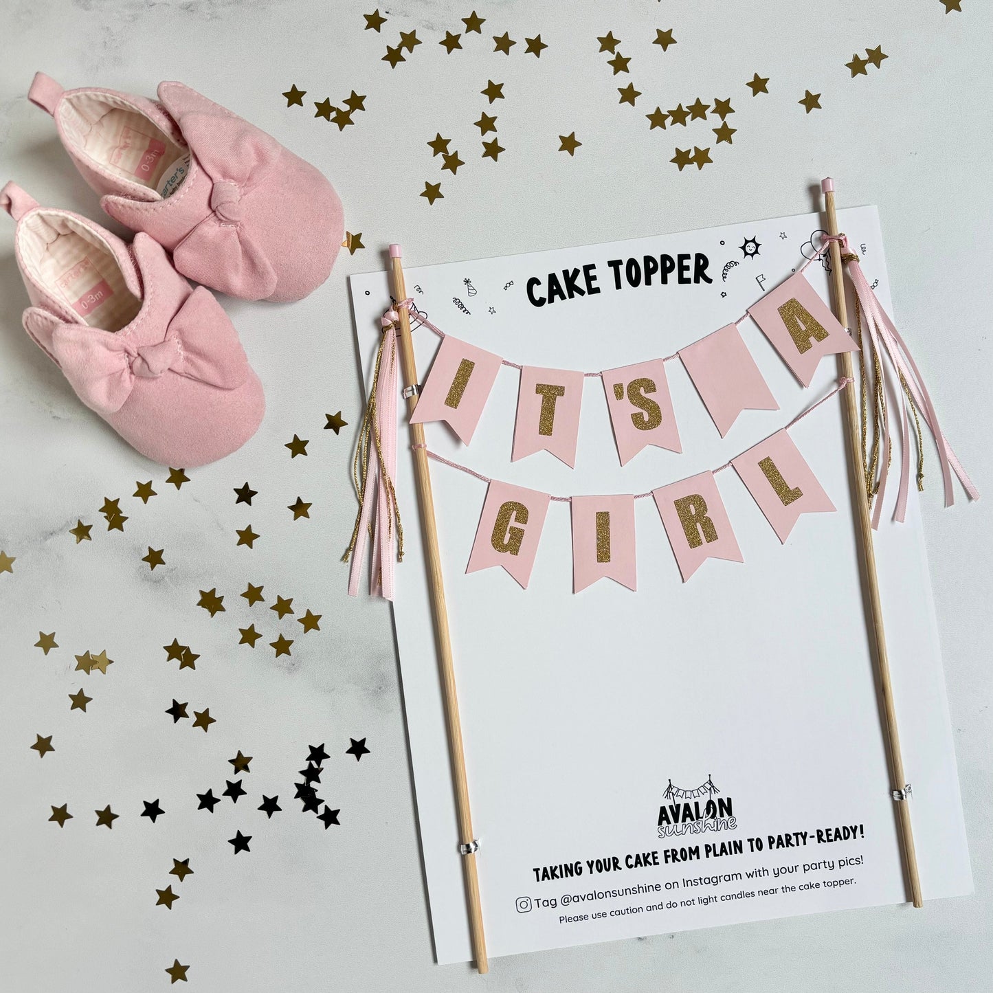 baby shower cake topper with text "IT'S A GIRL" with gold letters against a light pink background