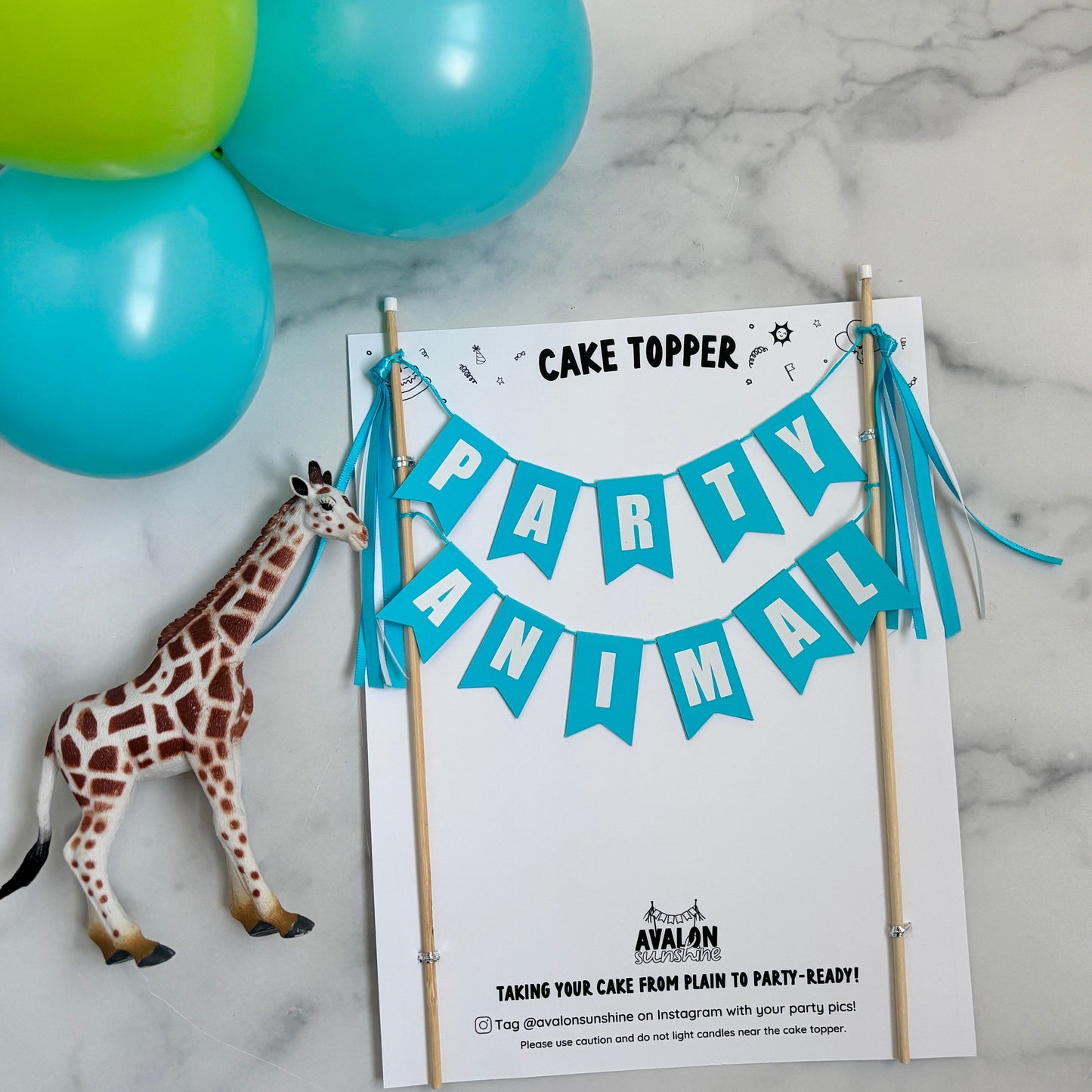 cake topper banner with wording PARTY ANIMAL in turquoise - shown with a plastic giraffe and balloons | personalized cake toppers by Avalon Sunshine