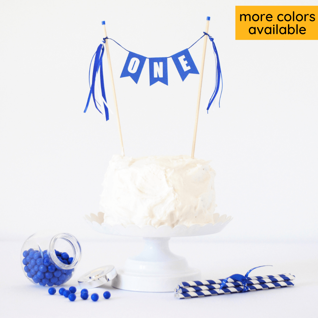 ONE first birthday cake topper royal blue shown on a white smash cake
