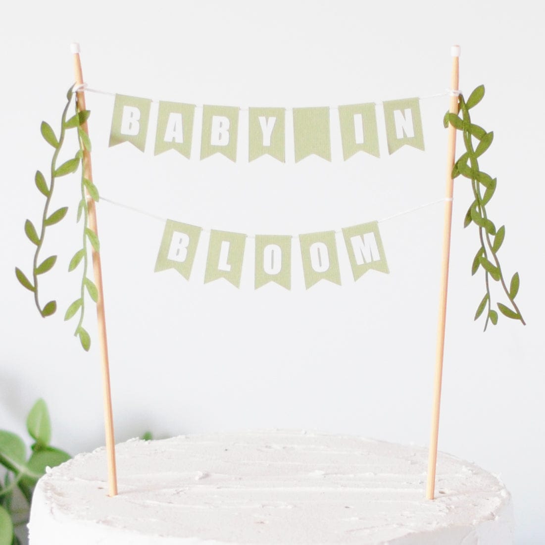 baby in bloom cake topper - two tiered sage green paper flags with leafy ribbon tassels