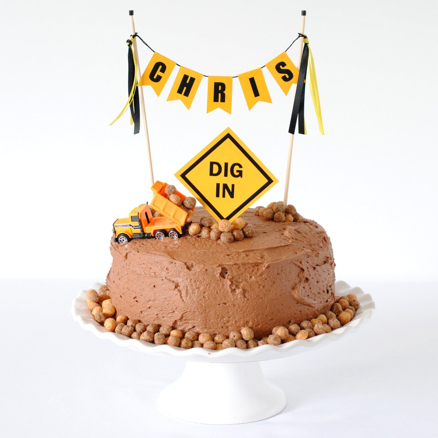 chocolate cake  with toy dump truck for construction theme party with yellow and black construction sign cake topper