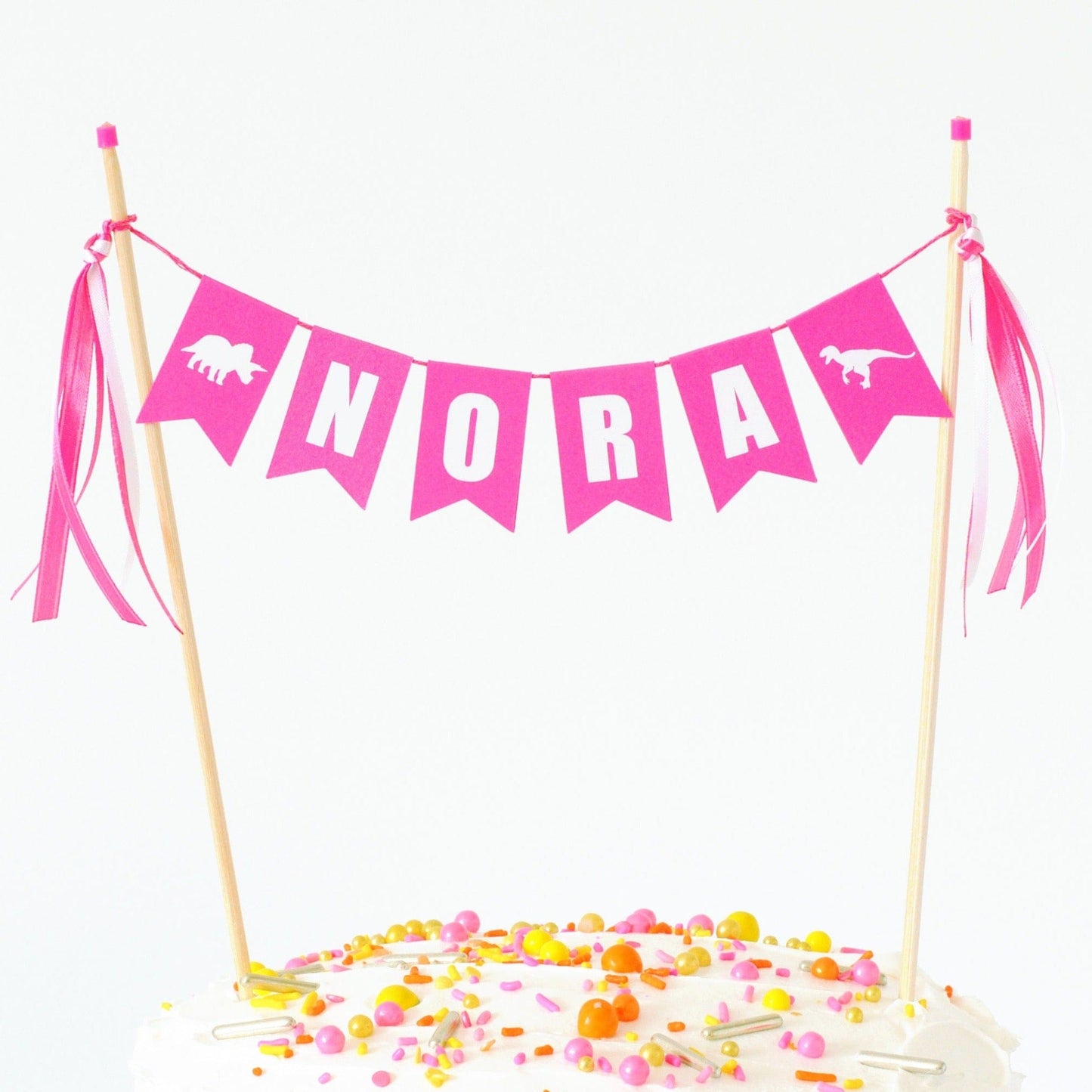 bright pink cake topper name banner with dinosaur flags at each end for girls dinosaur birthday