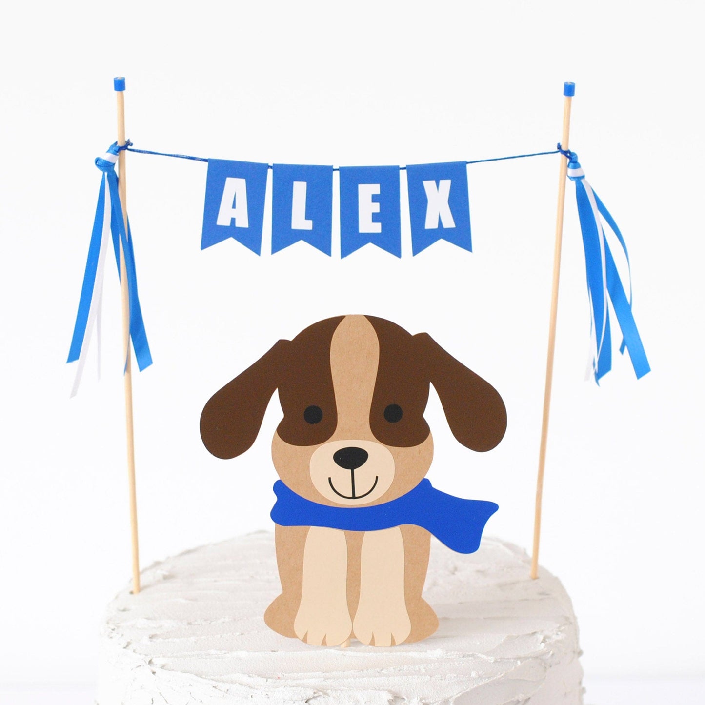 cake topper for dog theme birthday party with brown dog wearing a blue scarf and blue name banner