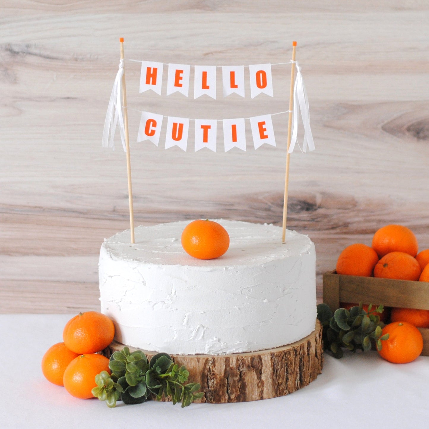 Hello Cutie baby shower cake topper with white ribbons and clementine decorations