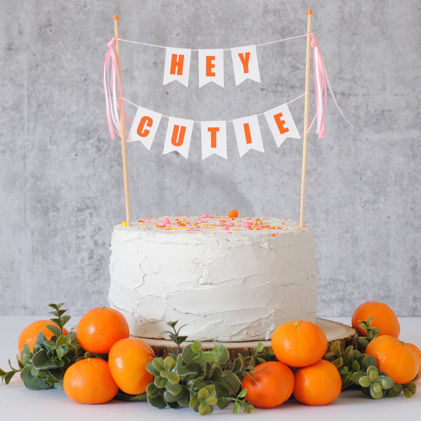 hey cutie baby shower cake topper with orange letters and pink ribbons