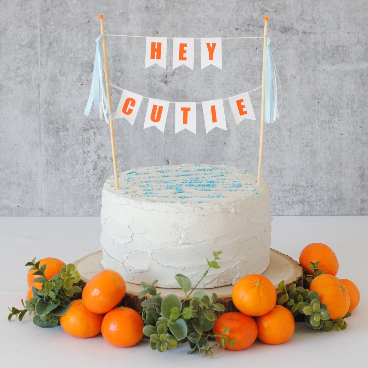hey cutie baby shower cake topper with orange letters and blue ribbons