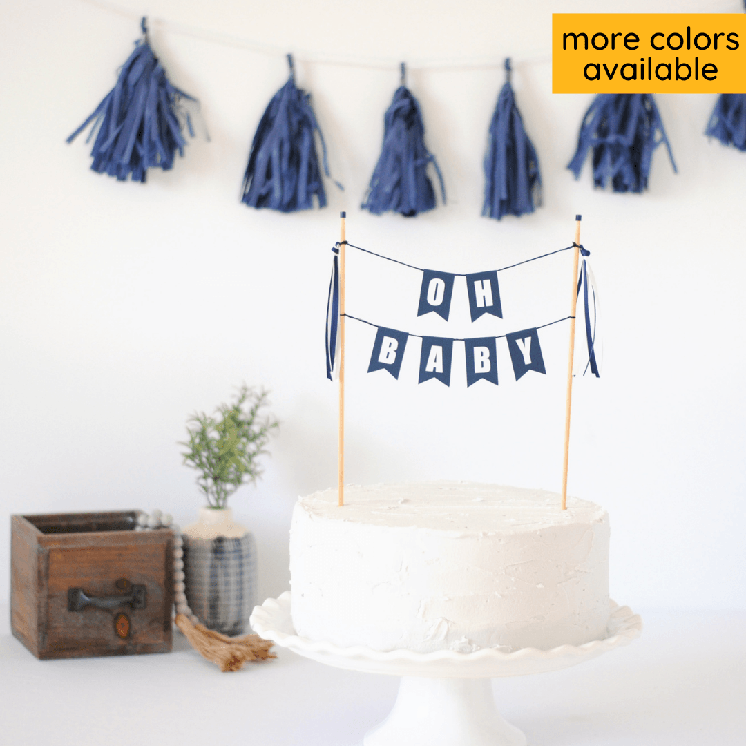 "oh baby" baby shower cake topper in navy blue with white letters shown on a white cake
