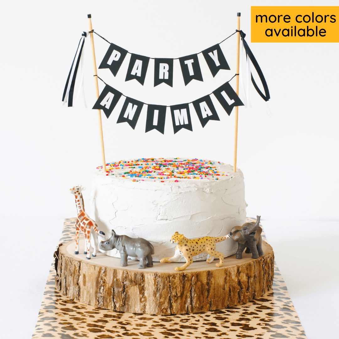 black and white party animal cake topper banner with mini toy animals around the cake
