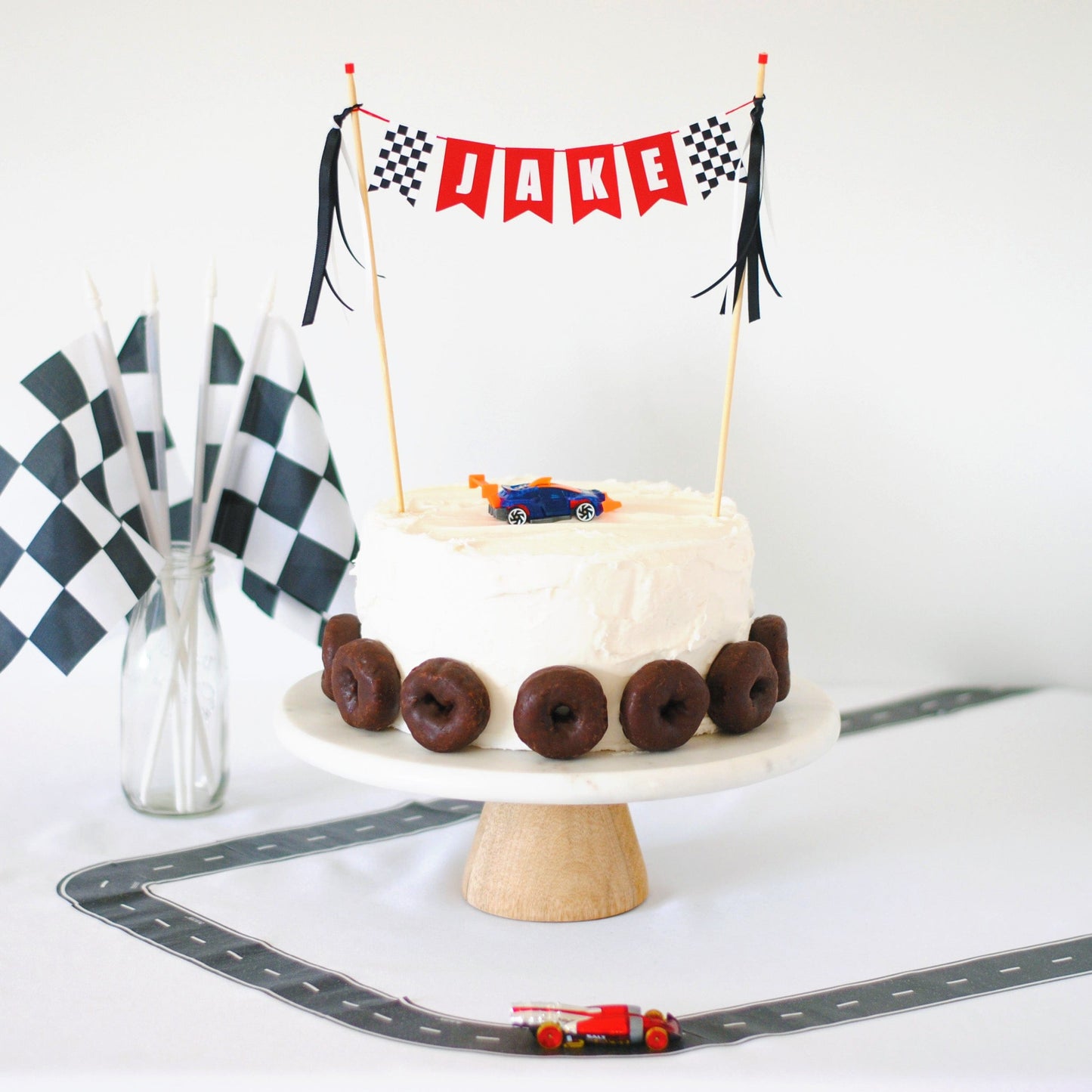 race car theme birthday cake table with personalized cake topper,  cake, race track and checkered flags