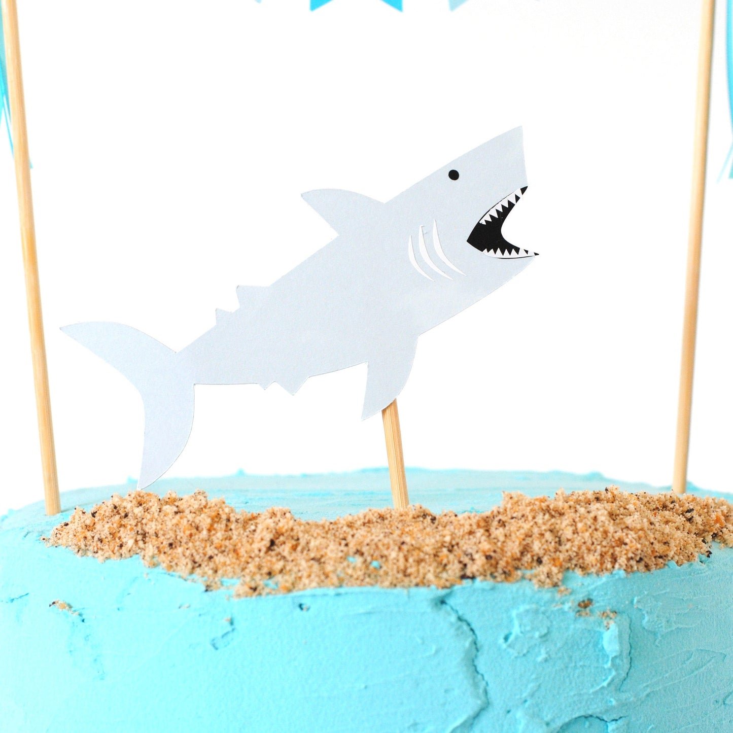 close-up view of paper shark cake topper shown jumping out of the cake