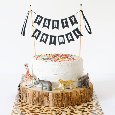 party animal cake topper on a birthday cake with plastic animals