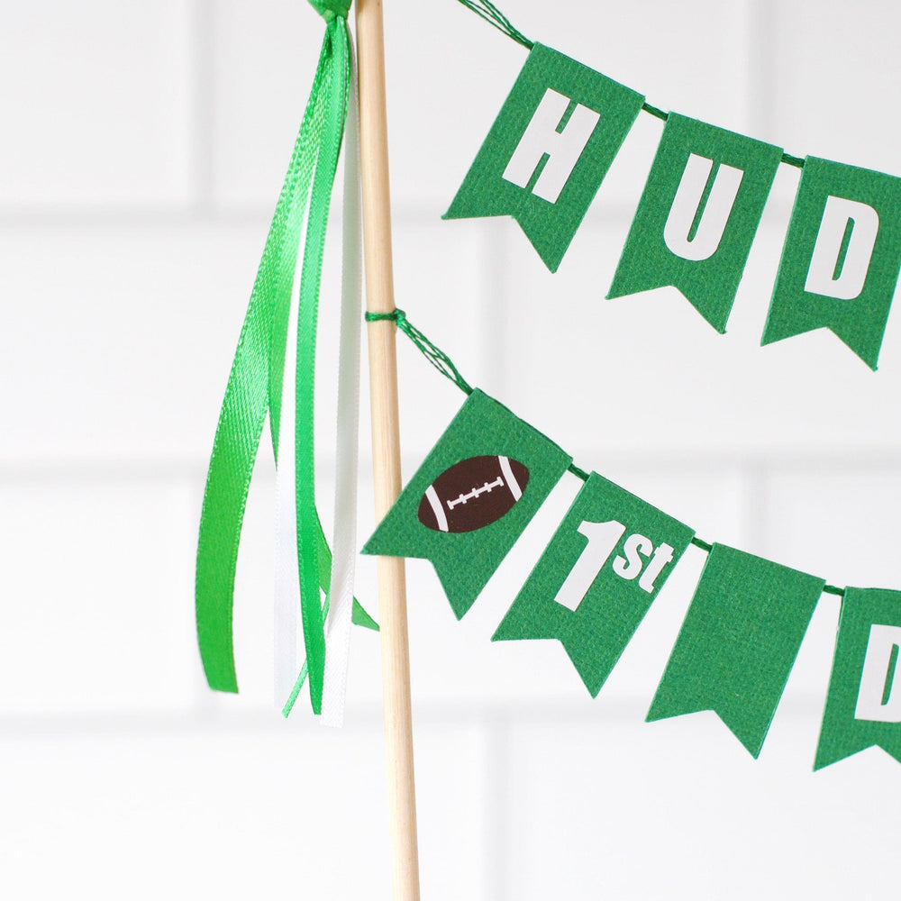 
                  
                    Green cake topper banner with 'HUDSON'S 1st DOWN' text on a white background and a football theme | personalized cake toppers by Avalon Sunshine
                  
                