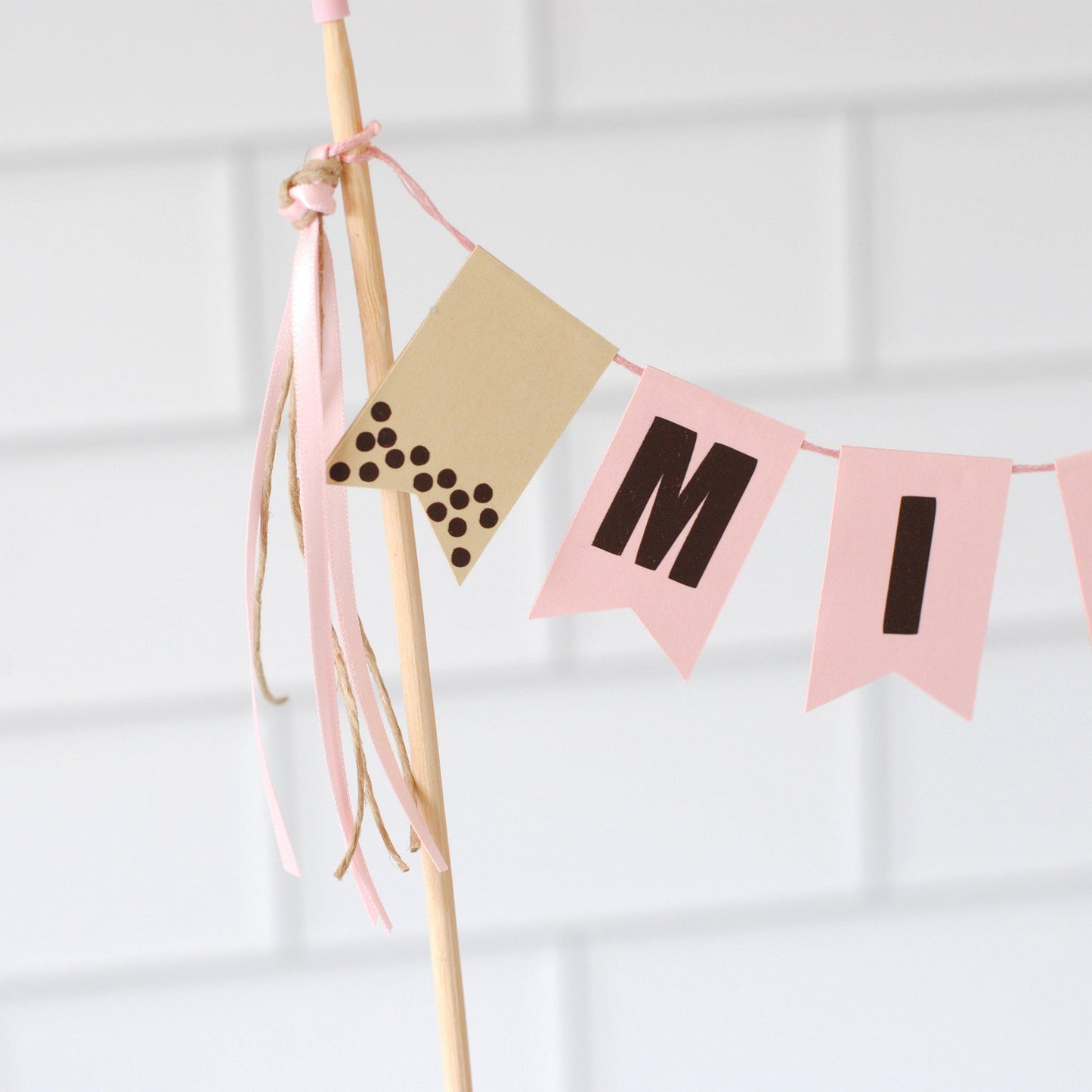 
                  
                    Close up view of cake topper banner for a Boba theme. Personalized flags with name and a beige flag with dark brown dots to look like boba
                  
                