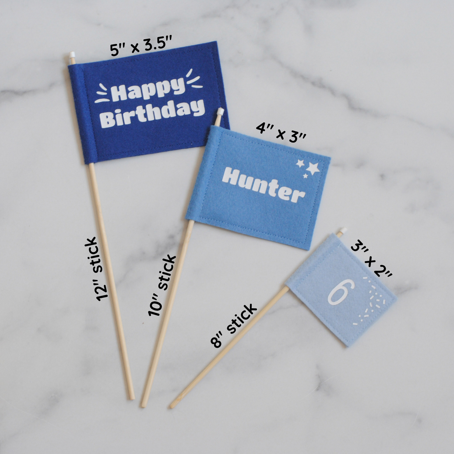 
                  
                    Set of 3 felt flag cake toppers in shades of blue. Large flag with HAPPY BIRTHDAY, medium flag personalized with name HUNTER, and small flag with age 6.  Shown flat with measurements of sticks and flags. 
                  
                