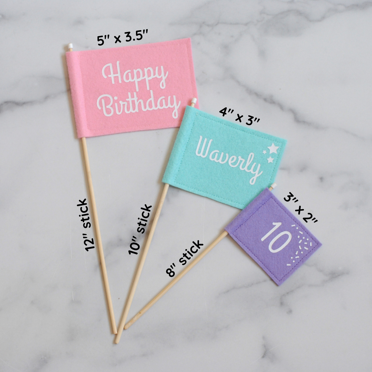 
                  
                    Felt flag cake topper set with pastel colors: large pink HAPPY BIRTHDAY flag, medium aqua blue NAME flag, and small purple AGE flag shown flat with measurements of flags and sticks
                  
                