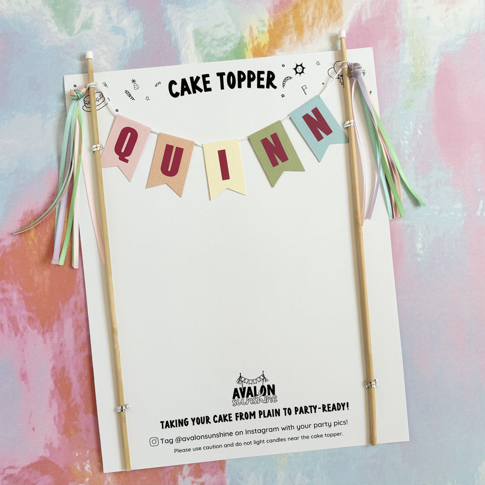 
                  
                    pastel rainbow colors name cake banner with dark pink  and pastel rainbow ribbon tassels | cake toppers by Avalon Sunshine
                  
                