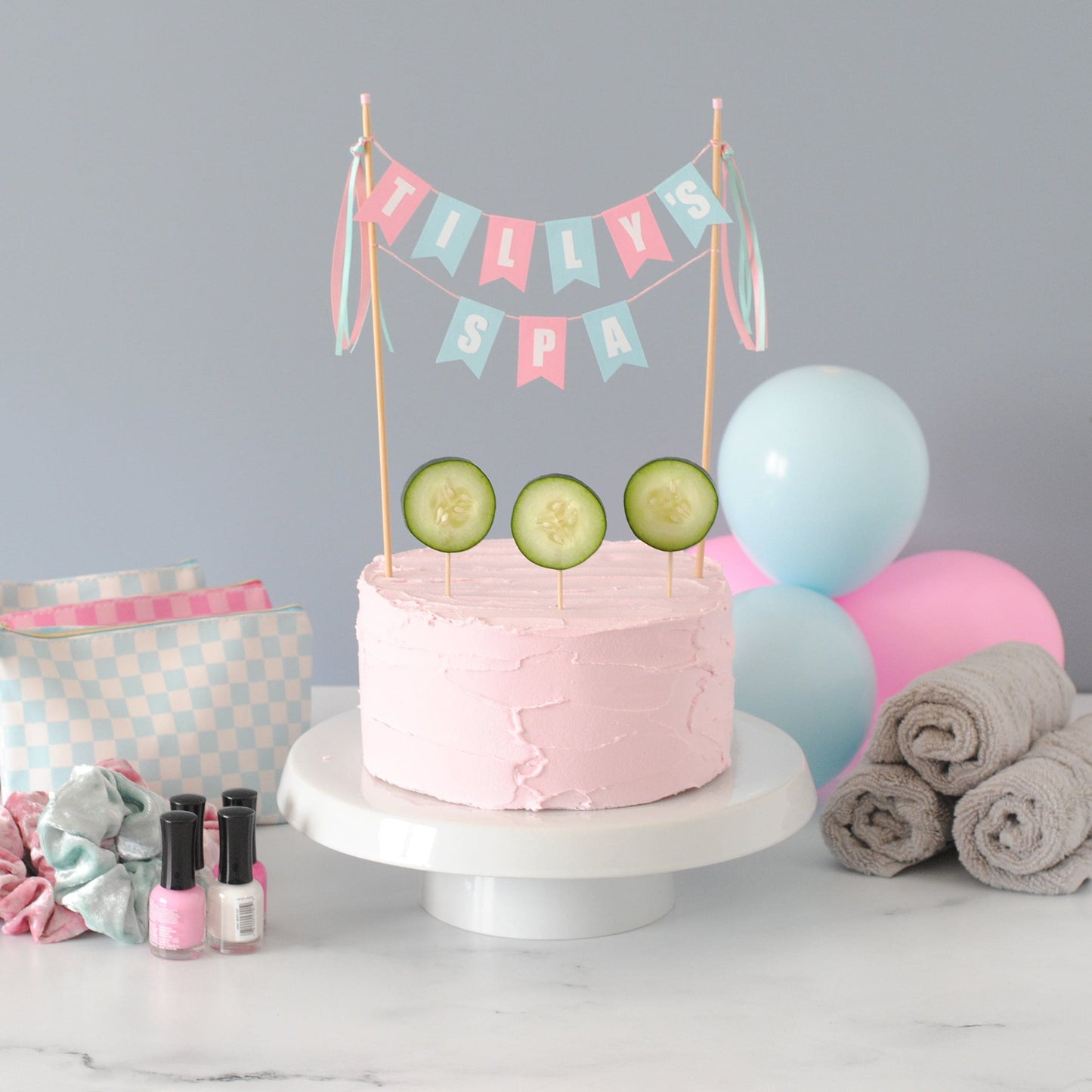 two tier cake topper for spa cake topper  - personalized to say TILLY'S SPA. Shown on a pink birthday cake decorated with cucumber slices and spa party supplies behind the cake