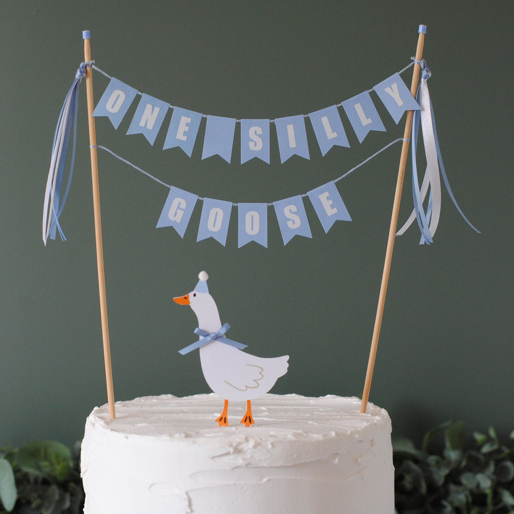 
                  
                    Cake with a goose topper and 'One Silly Goose' banner on a dark background | cake topper by Avalon Sunshine
                  
                
