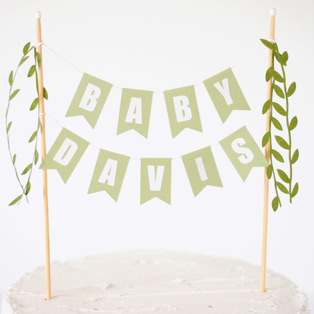 
                  
                    baby shower cake topper personalized with baby name and green leafy ribbons
                  
                