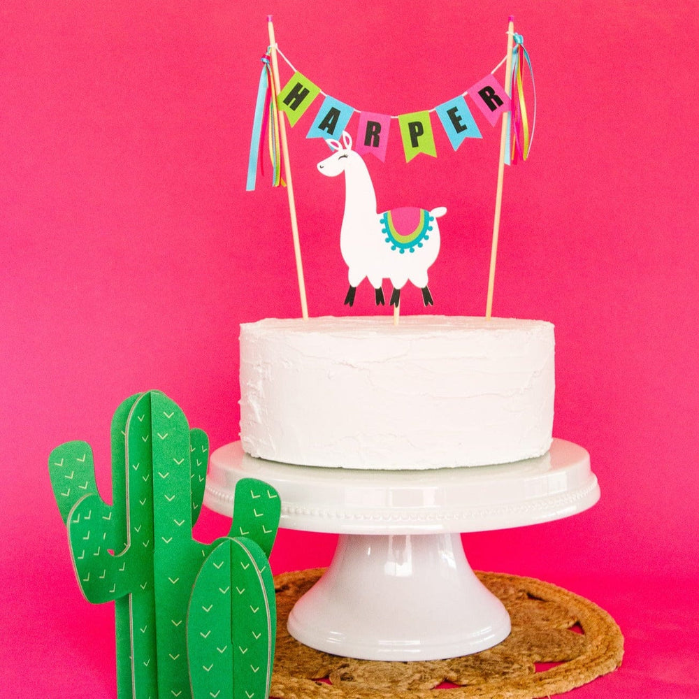 
                  
                    llama cake topper set with paper llama and a personalized name banner in green blue and pink
                  
                