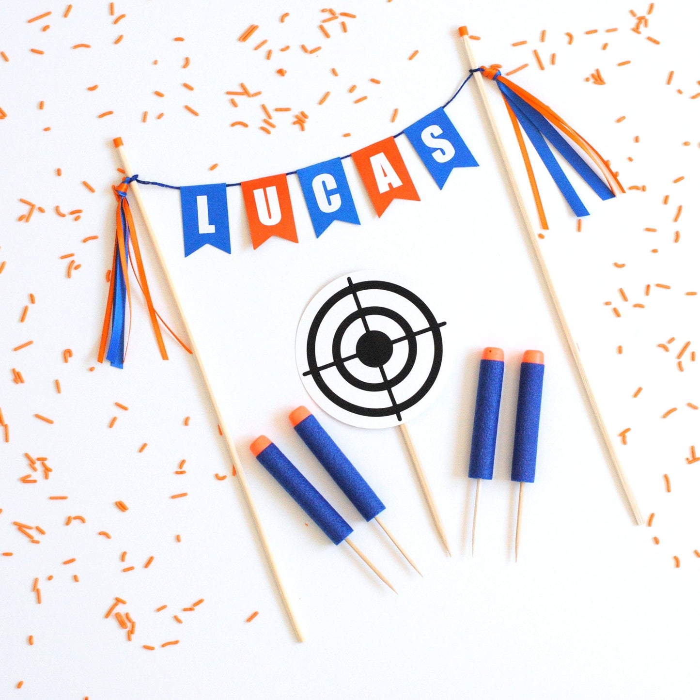 
                  
                    foam dart cake topper set with name banner, round target and blue with orange foam darts
                  
                