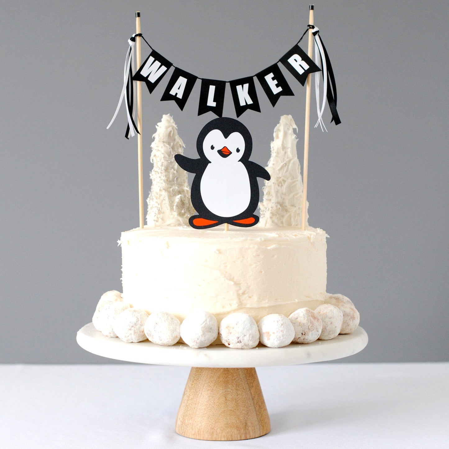 
                  
                    penguin cake topper set for kids birthday cake with paper penguin and black and white name banner
                  
                