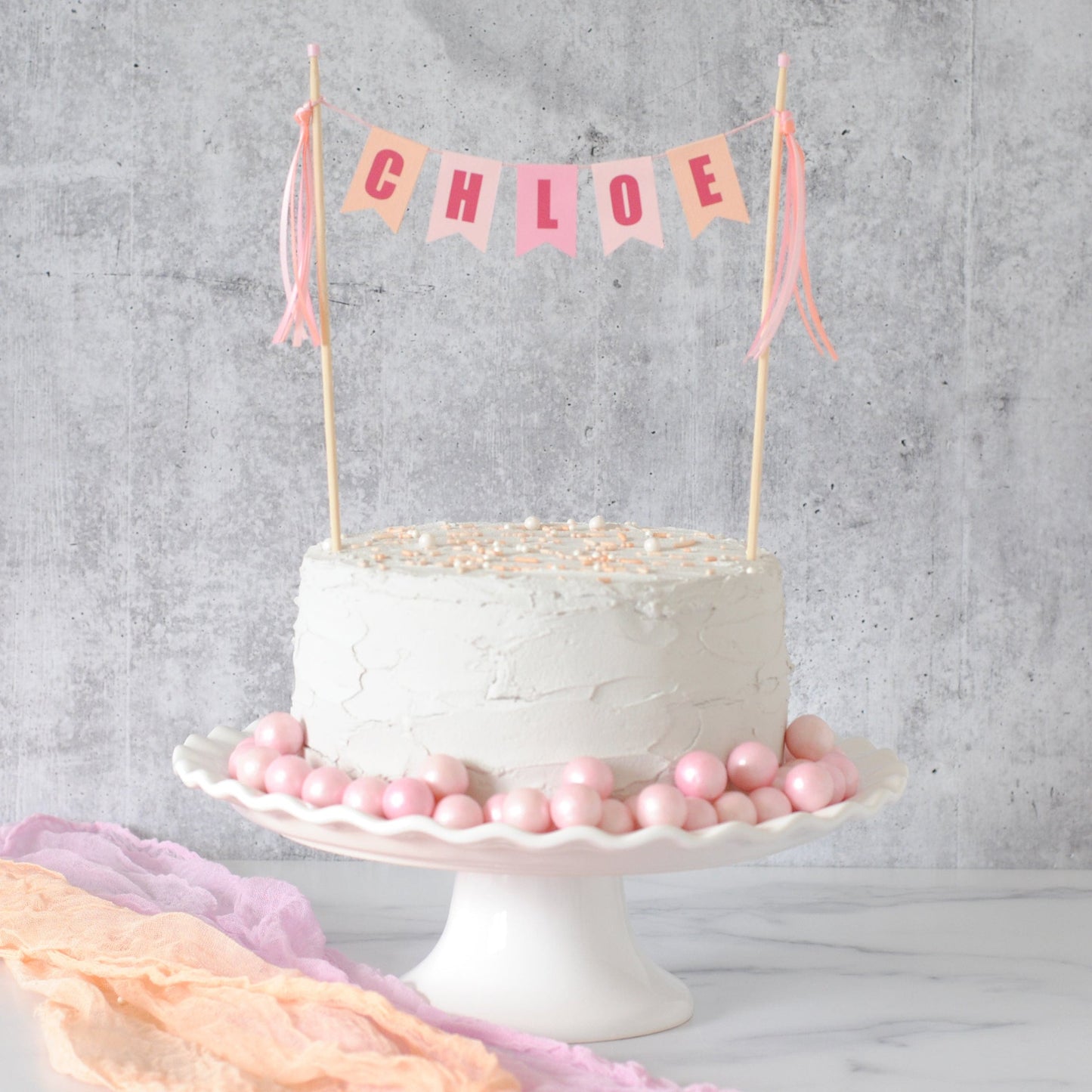 girls birthday cake topper in shades of pink and peach shown on a white cake 