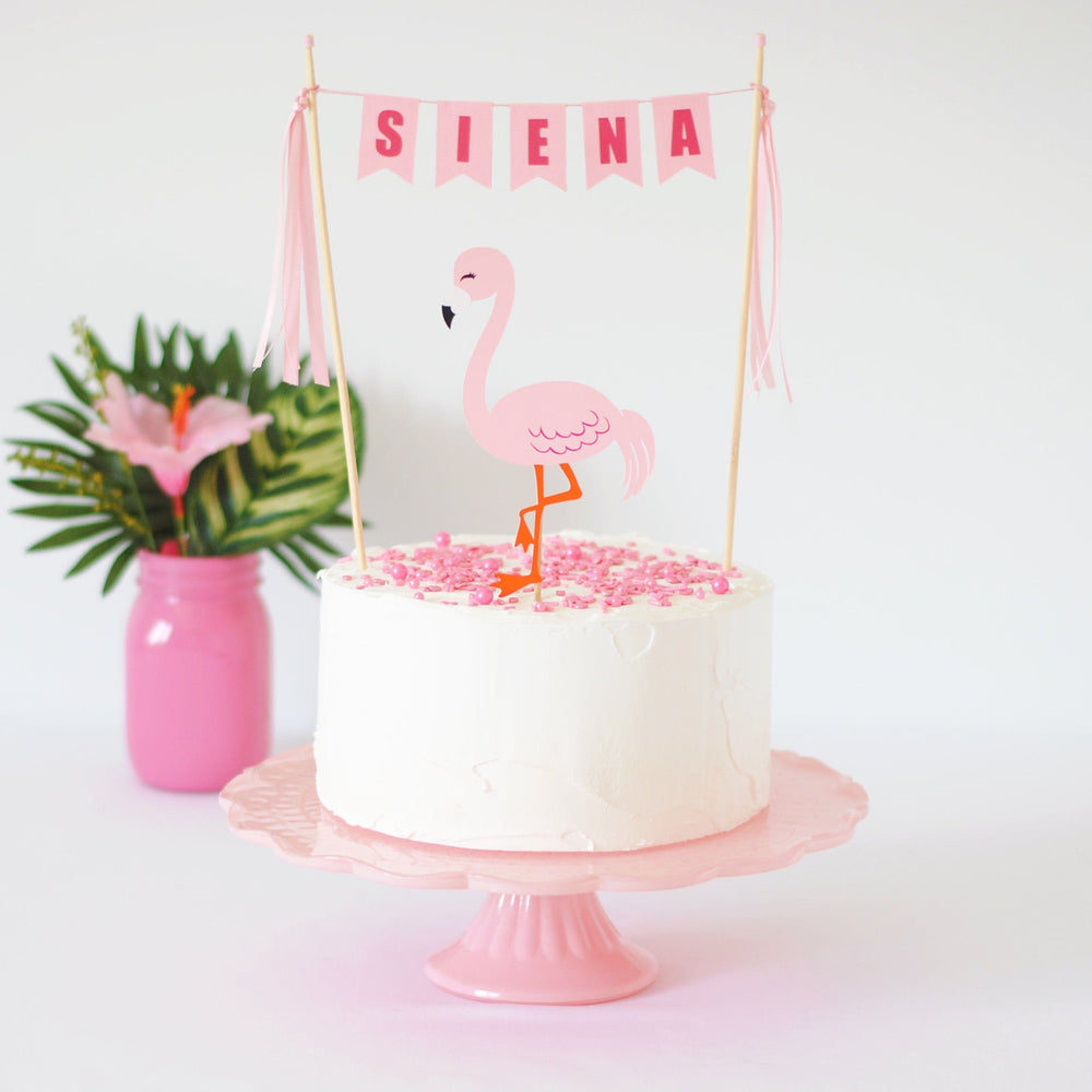 
                  
                    pink flamingo cake topper on white cake with pink sprinkles
                  
                
