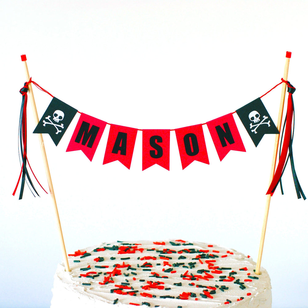 
                  
                    pirate theme birthday cake topper in red and black personalized with name and skull  and crossbones
                  
                