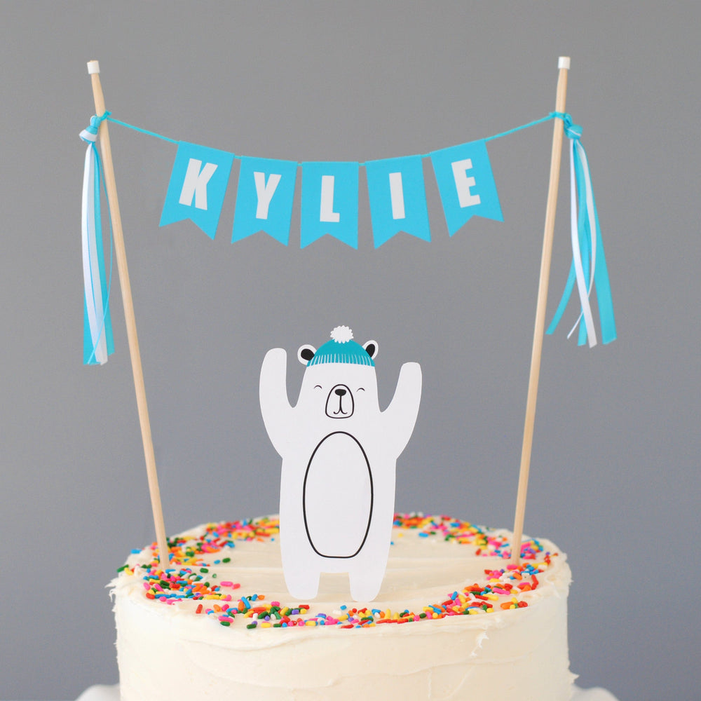 
                  
                    personalized polar bear cake topper set with paper polar bear and name banner in turquoise and white
                  
                