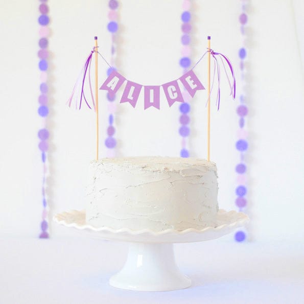 
                  
                    purple cake banner personalized with name on a white cake
                  
                