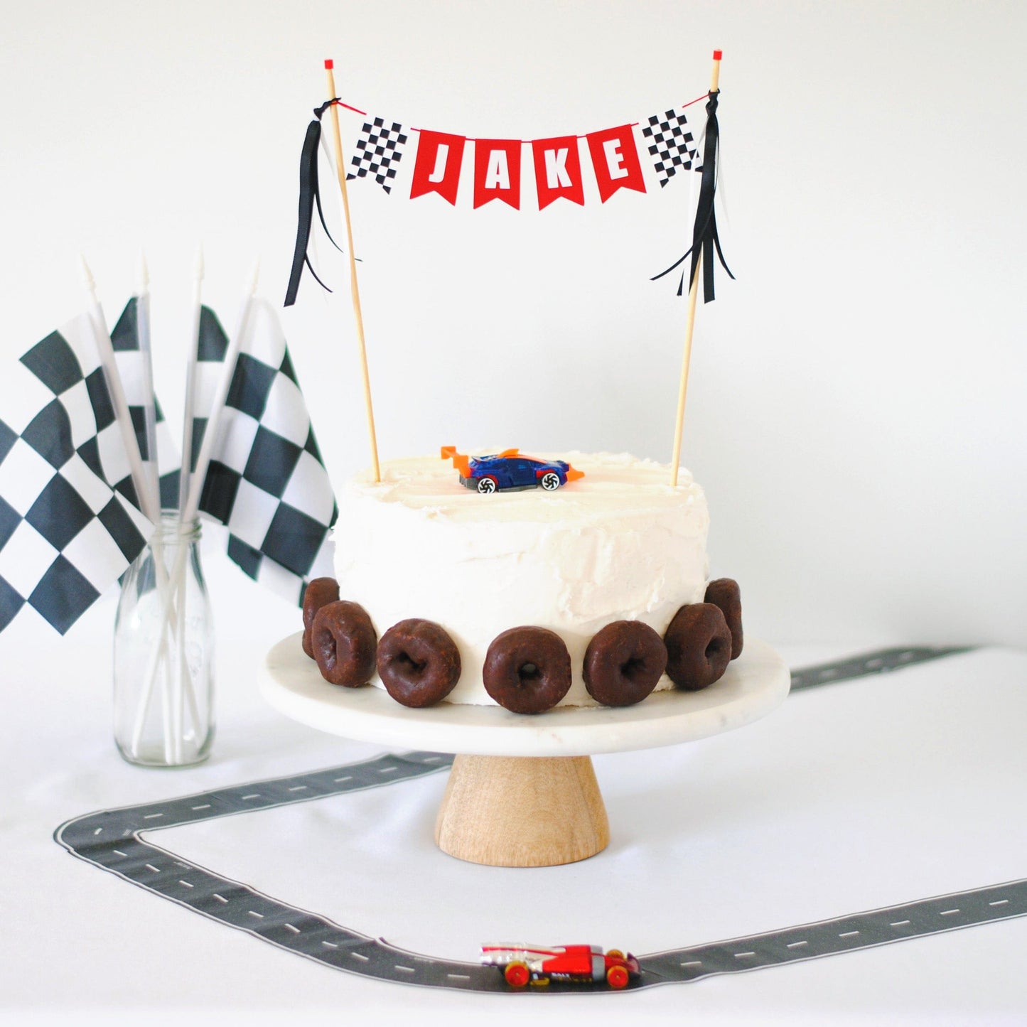 
                  
                    race car theme birthday cake table with personalized cake topper,  cake, race track and checkered flags
                  
                