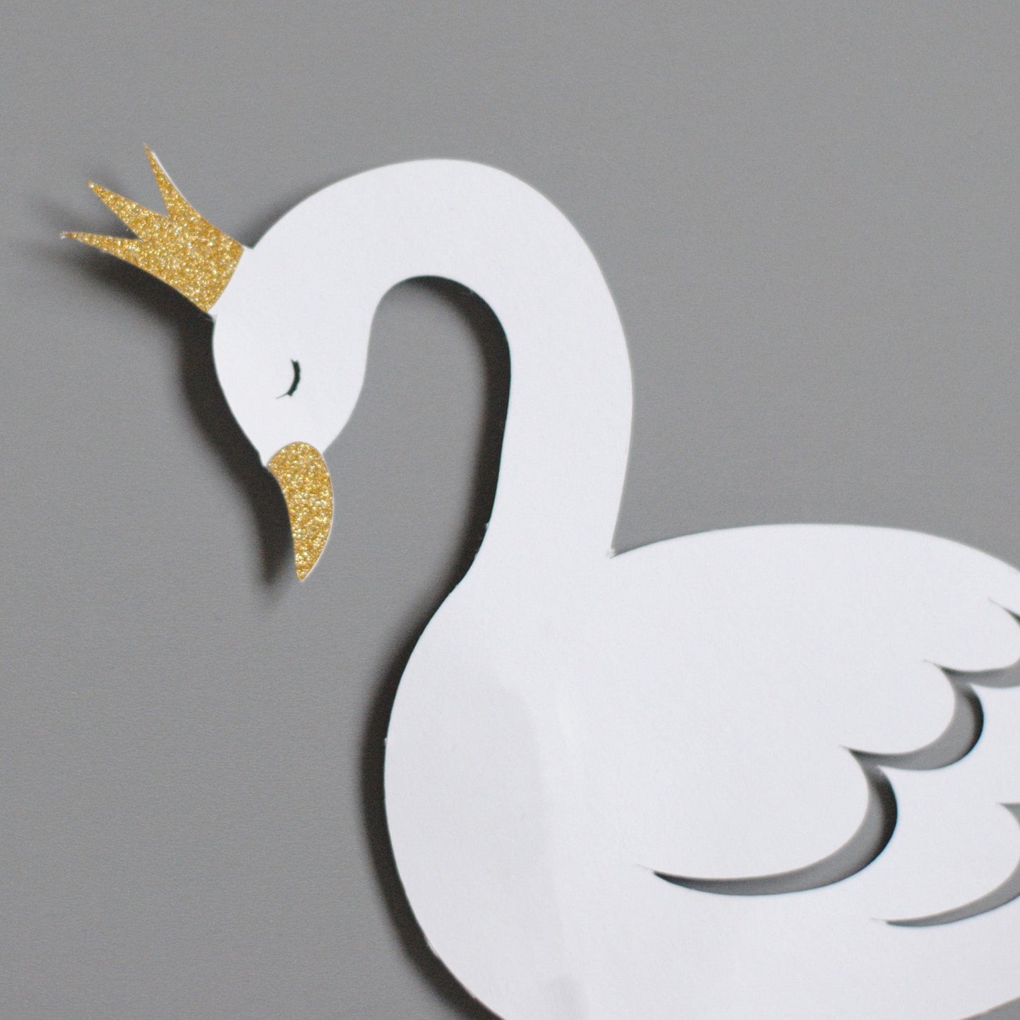 
                  
                    close-up of swan cake topper with gold glitter crown
                  
                