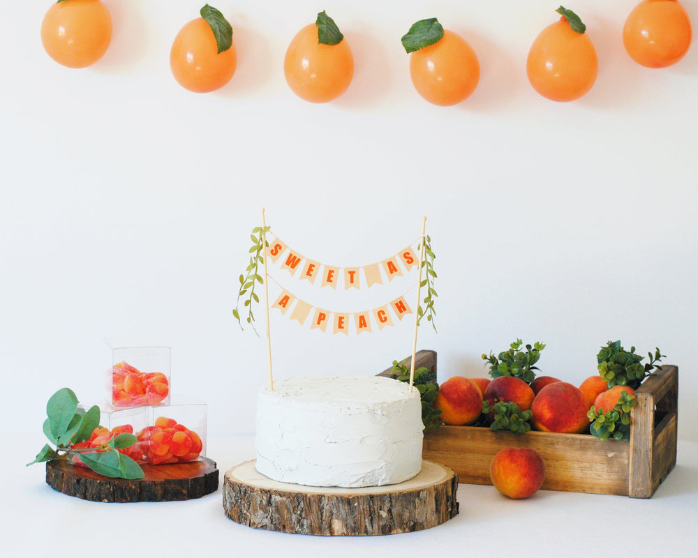 
                  
                    Sweet as a Peach baby shower cake topper shown with fresh peaches and candy peaches
                  
                