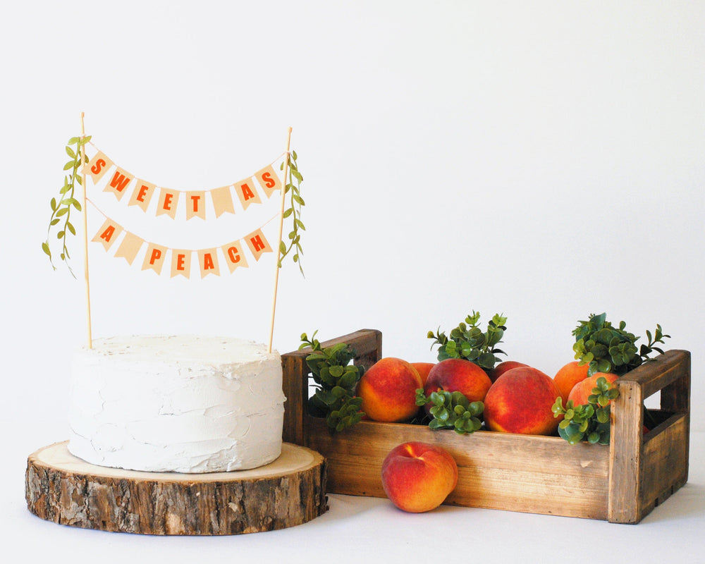 
                  
                    Sweet as a peach baby shower cake topper shown with fresh peaches in a wood crate
                  
                