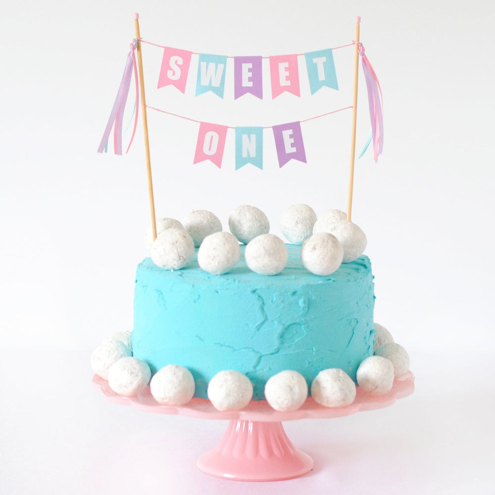 
                  
                    1st birthday cake decorated with donut holes and a cake topper with wording SWEET ONE | cake topper made by Avalon Sunshine
                  
                